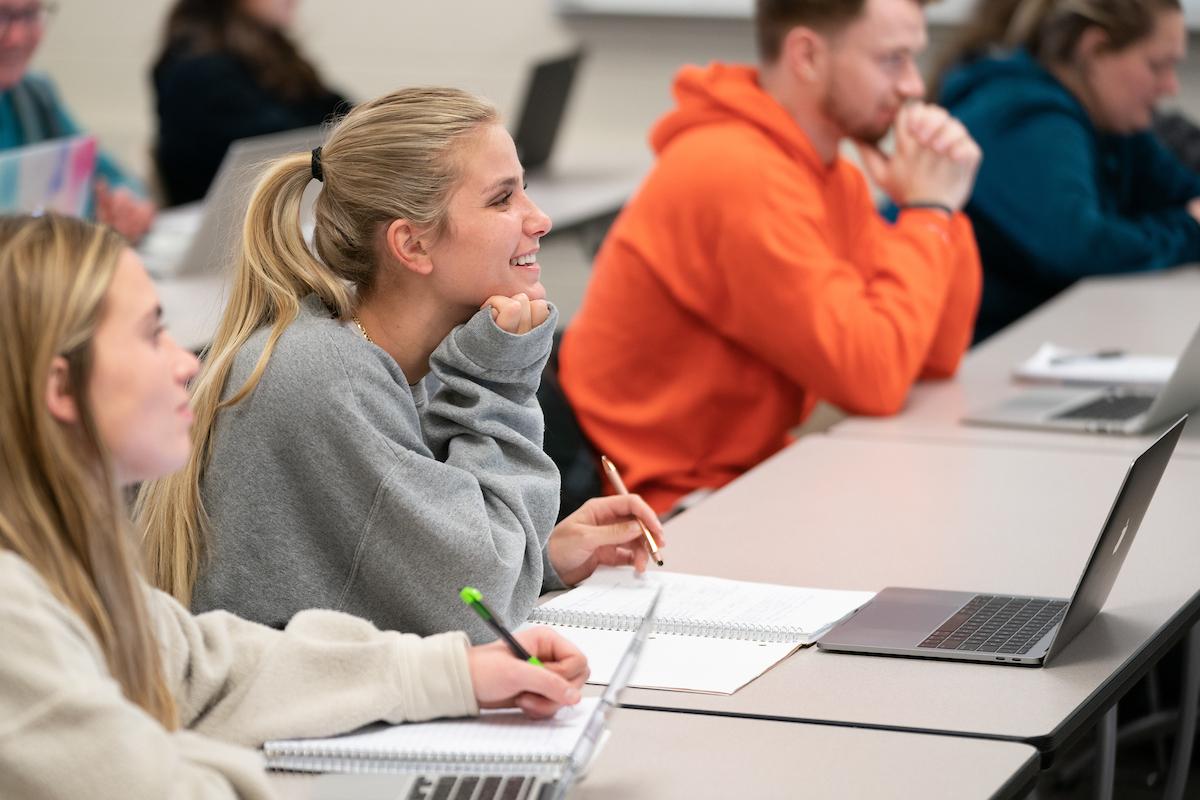 Student at desk taking notes smiling